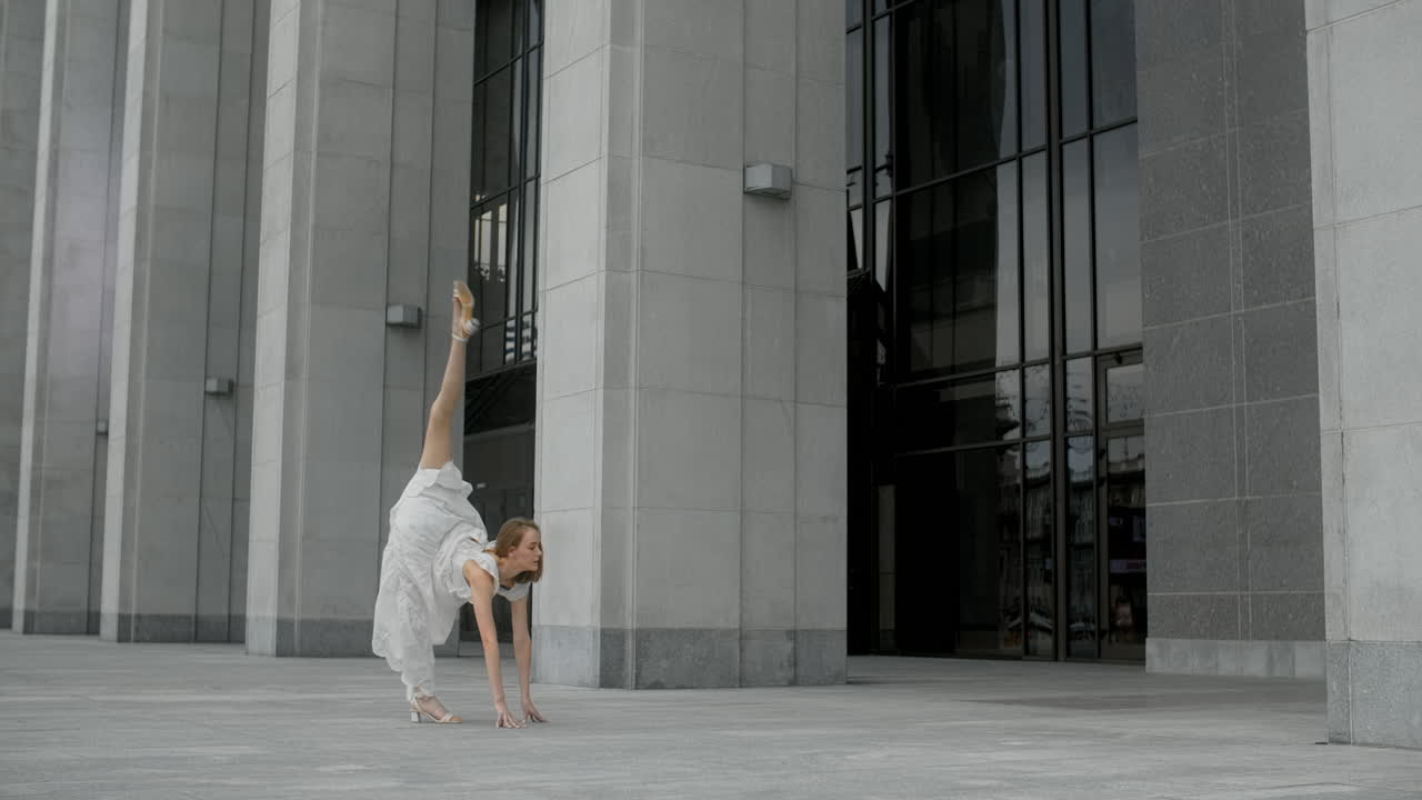 Woman performing a dance pose in front of a modern building