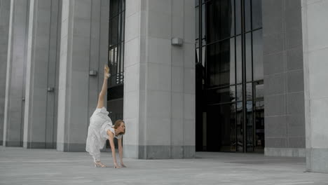 woman performing a dance pose in front of a modern building