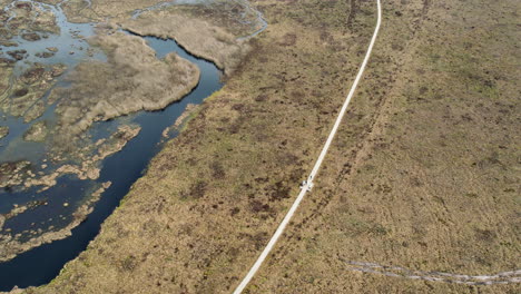 hiking boardwalk across expansive barren wetland, birds eye view, aerial circling