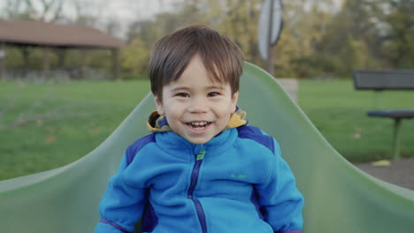 carefree asian kid rides on a merry-go-round, smiles and enjoys a walk.