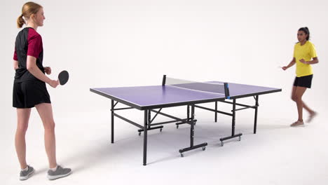 playing table tennis, two women competing intensely in studio setting
