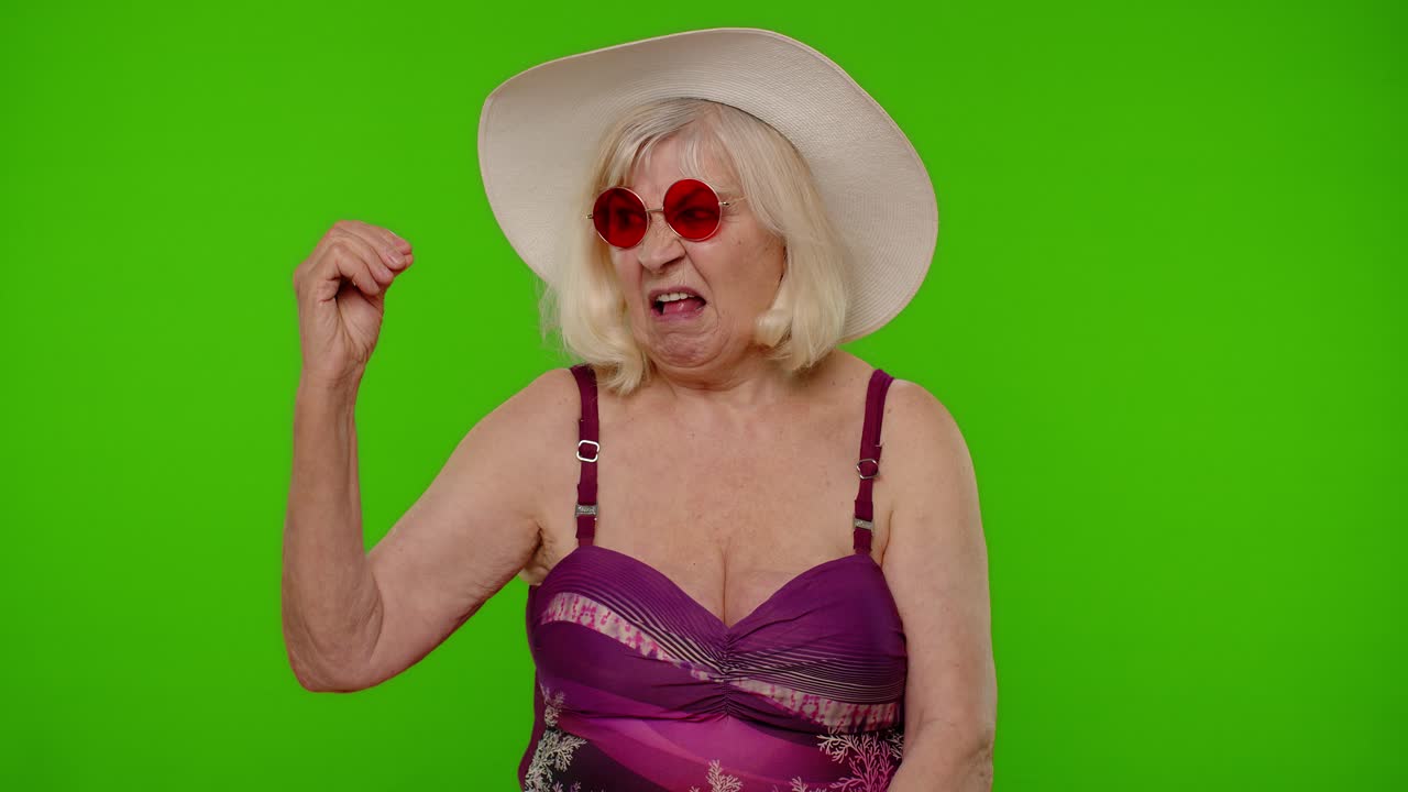 초록색 스크린에 수영복, 모자, 선글라스를 입은 고위 여성
