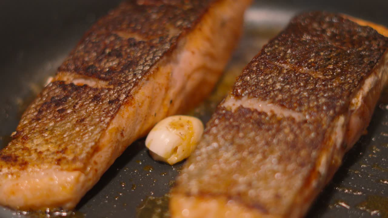 Freshly Cooked Wild Caught Scottish Salmon in Frying Pan with Garlic and Butter Seasoned with Salt and Pepper. Delicious Dinner Ready to Serve at Home or Restaurant 4K