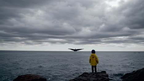a child looking out at a whale in the ocean