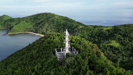 Aerial-footage-captures-the-stunning-Bote-Lighthouse-in-Catanduanes,-Philippines-atop-a-forested-hill,-while-zooming-out-to-reveal-the-whole-island-and-surrounding-ocean