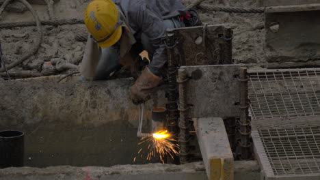 trabajador que opera con chorro de gas para cortar tubos metálicos