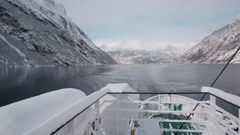 Vídeo-En-Primera-Persona-De-Un-Viaje-En-Ferry-A-Través-Del-Fiordo-De-Geiranger-En-Invierno,-Que-Presenta-Impresionantes-Vistas-De-Montañas-Cubiertas-De-Nieve,-Un-Cielo-Brillante-Y-Reflejos-En-El-Fiordo.