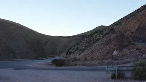 Truck-navigates-a-mountain-pass-in-the-Andes,-curving-between-Purmamarca-and-Salinas-Grandes