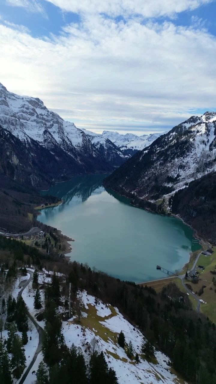 Klöntalersee, valle di Klöntal, Alpi svizzere innevate, inverno alpino, ripresa aerea verticale da drone.