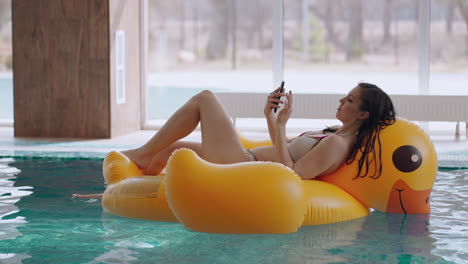 relax-time-in-swimming-pool-in-wellness-center-young-woman-in-bikini-is-lying-on-inflatable-circle