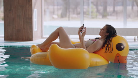relax time in swimming pool in wellness center young woman in bikini is lying on inflatable circle