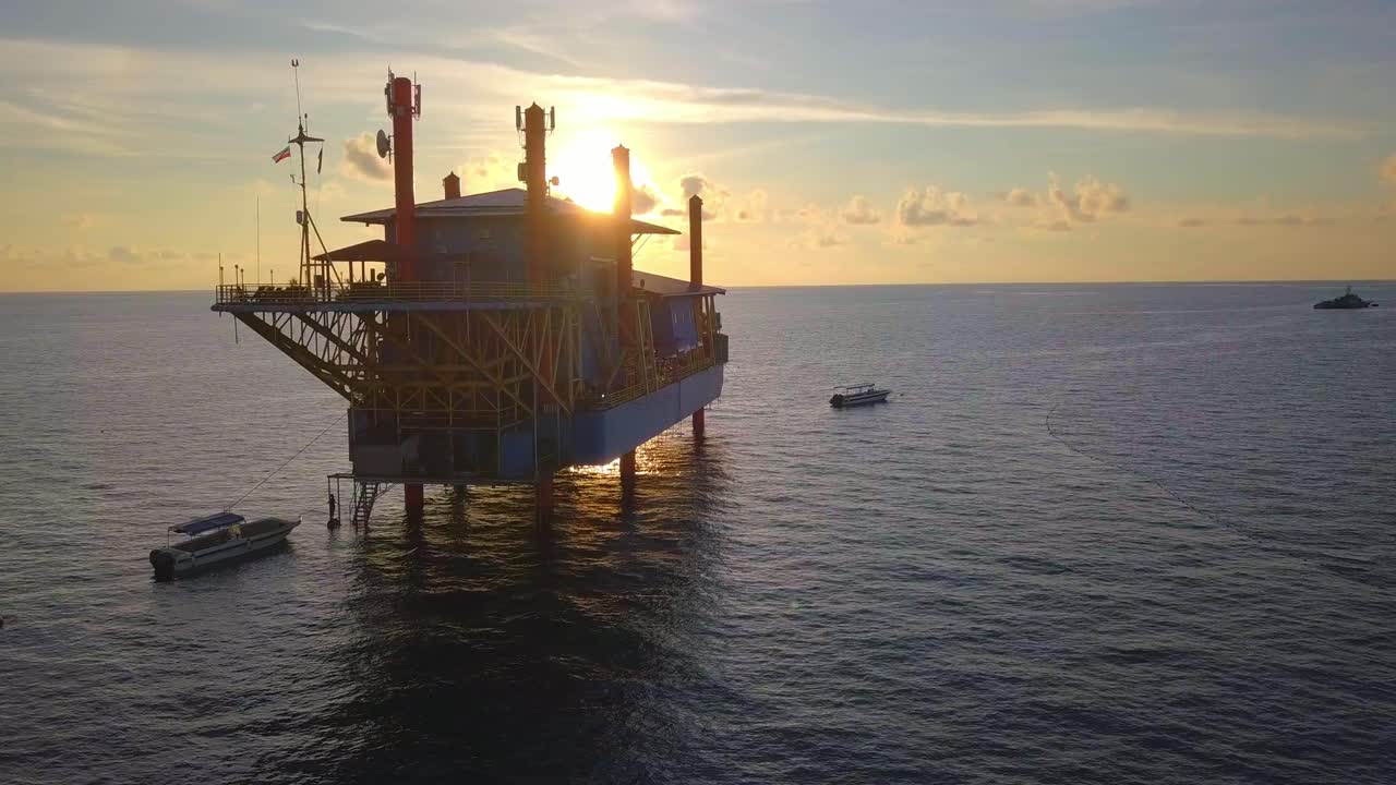 Droneflyvning ved betagende solnedgang over havet omkring en olieplatform i Mabul, Malaysia