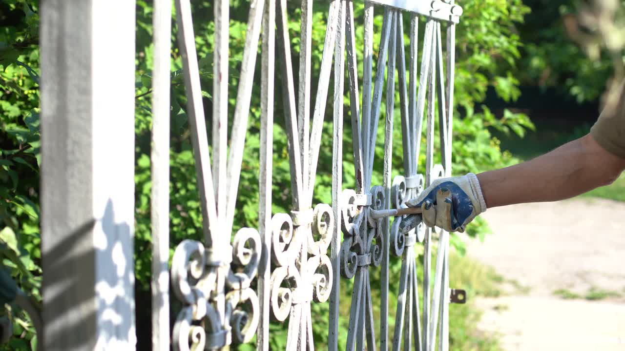 un uomo dipinge un cancello e una recinzione