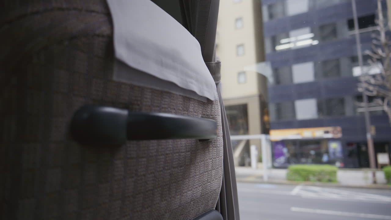 Udsigten fra bussen viser livet i Tokyo, Japan, med moderne bygninger. Folk går langs fortovet og skaber en livlig atmosfære.