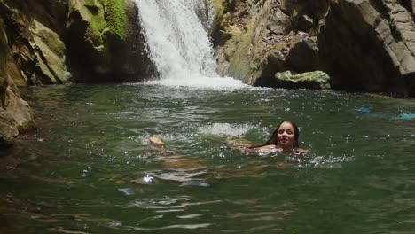 two girls in bikinis appreciate a tropical waterfall and river in the caribbean.