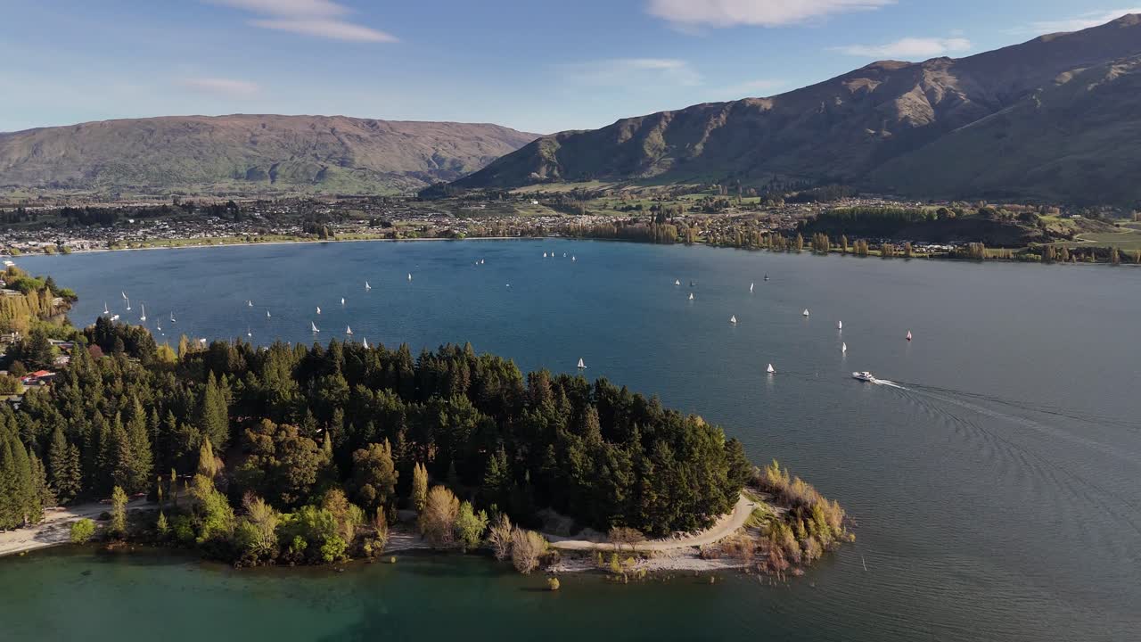 Filmato aereo cinematografico in 4K a 60 fps di una regata velica sul lago Wanaka, che mostra barche a vela che corrono sull'acqua blu con la città di Wanaka e le Alpi meridionali sullo sfondo