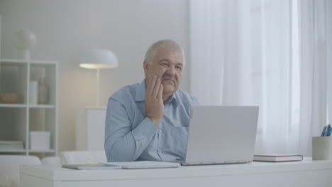 man-with-toothache-is-working-with-laptop-in-home-office-rubbing-cheek-sharp-pain-in-teeth-or-gum-problems-with-health-at-working-day