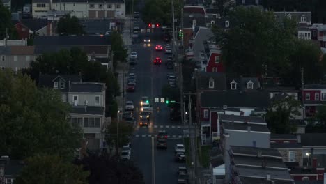 dusk falls on a busy residential street lined with houses and traffic lights