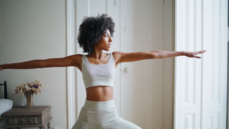 calm model practicing yoga home. african sportswoman stretching body making pose