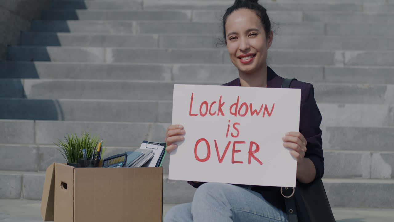 Woman Holding Sign Saying 'Lockdown is Over' on Stairs