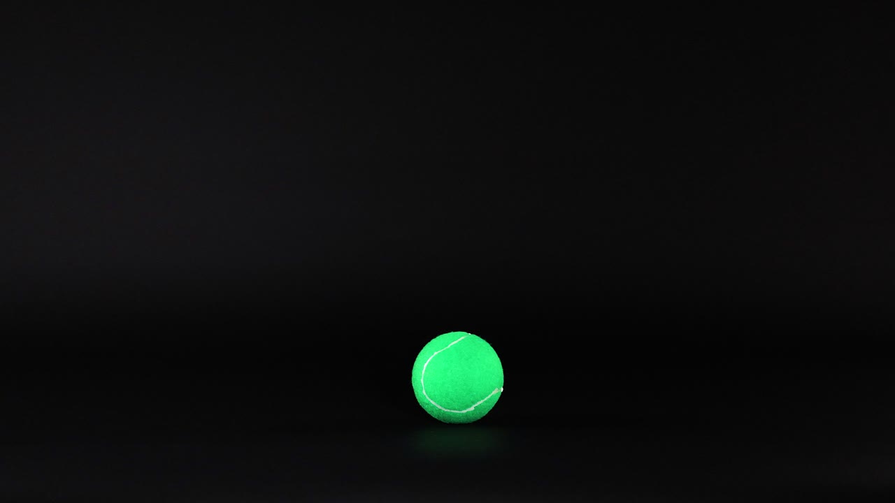 Tennis balls moving across a dark background
