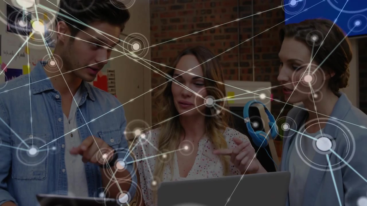 Man tapping tablet sparking network overlay showing data flow as team reviewing charts in tech hub