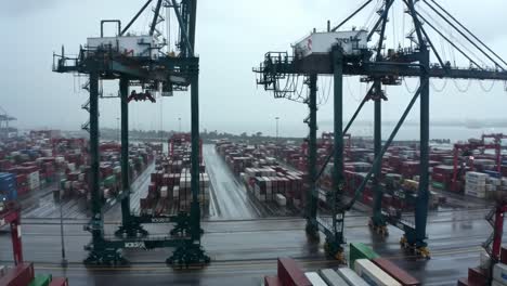 aerial view of a busy shipping port with cranes and containers under overcast skies, showcasing logistics operations in action
