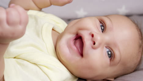 mother playing with baby son lying on bed in nursery