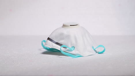hand lifting protective facial white mask mask ffp2 from threat like corona covid-19 virus on white backing that protects mouth and nose on plate capture in 4k 60fps