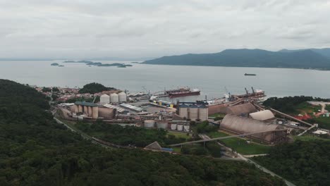 Aerial-view-of-Babitonga-Bay,-silos-and-barge-for-storage-and-transportation-of-bulk-in-port-of-São-Francisco-do-Sul,-Brazil