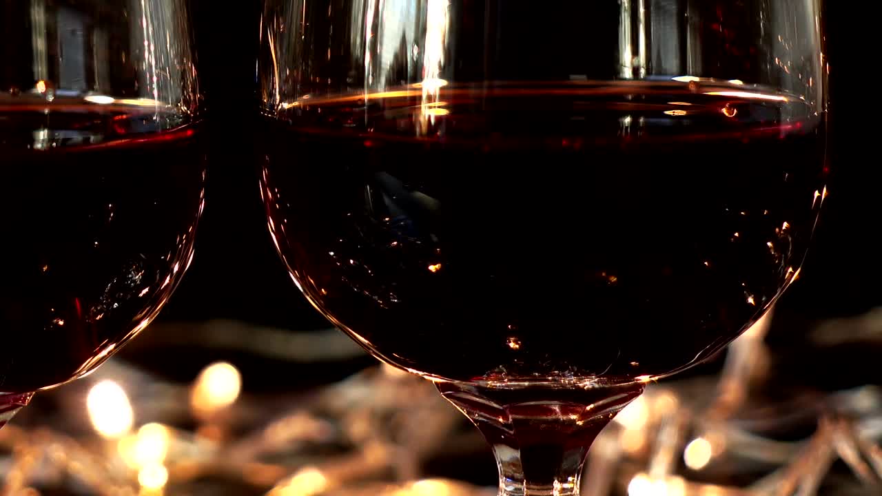 Taças de vinho e rosa contra o fundo de guirlandas brilhantes