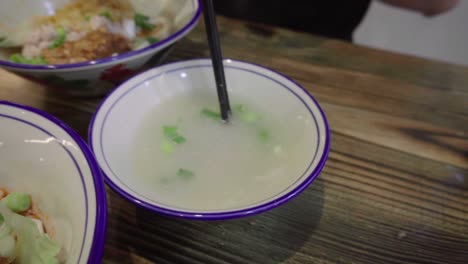 Traditional-Asian-Singaporean-noodles-soup-being-stirred-with-chop-sticks-in-slow-motion-Meepok-with-egg-and-minced-meat