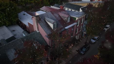 cozy american town as christmas lights decorate during snowfall at night