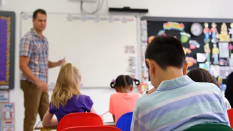 Vista-Lateral-De-Un-Profesor-Caucásico-Enseñando-A-Escolares-En-Una-Pizarra-En-El-Aula-4k