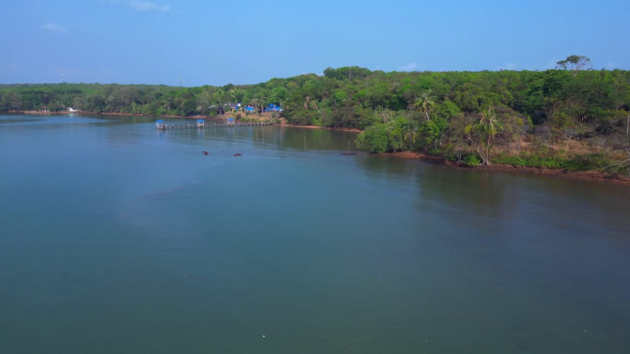 Koh Mak tropical island in Thailand showing luxury glamping tents on the coast near the pier surrounded by lush vegetation. Gorgeous aerial view flight pull in drone