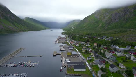 aerial dolly forward shot of the small town of gryllefjord nestled in the valley of cloud draped mountains on a magical summer day