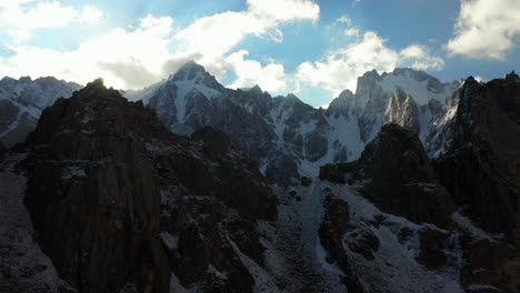 Toma-Aérea-Cinematográfica-épica-De-Drones-Mirando-A-Través-De-Las-Montañas-Para-Ver-Los-Picos-Del-Glaciar-Ak-sai-En-Kirguistán