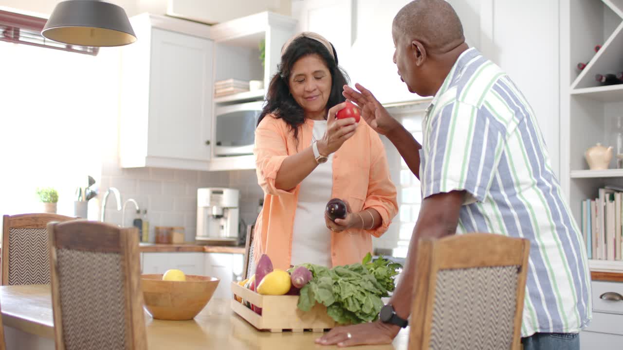 Femme tenant des légumes et offrant un poivron rouge, homme se penchant et sentant, préparant les provisions