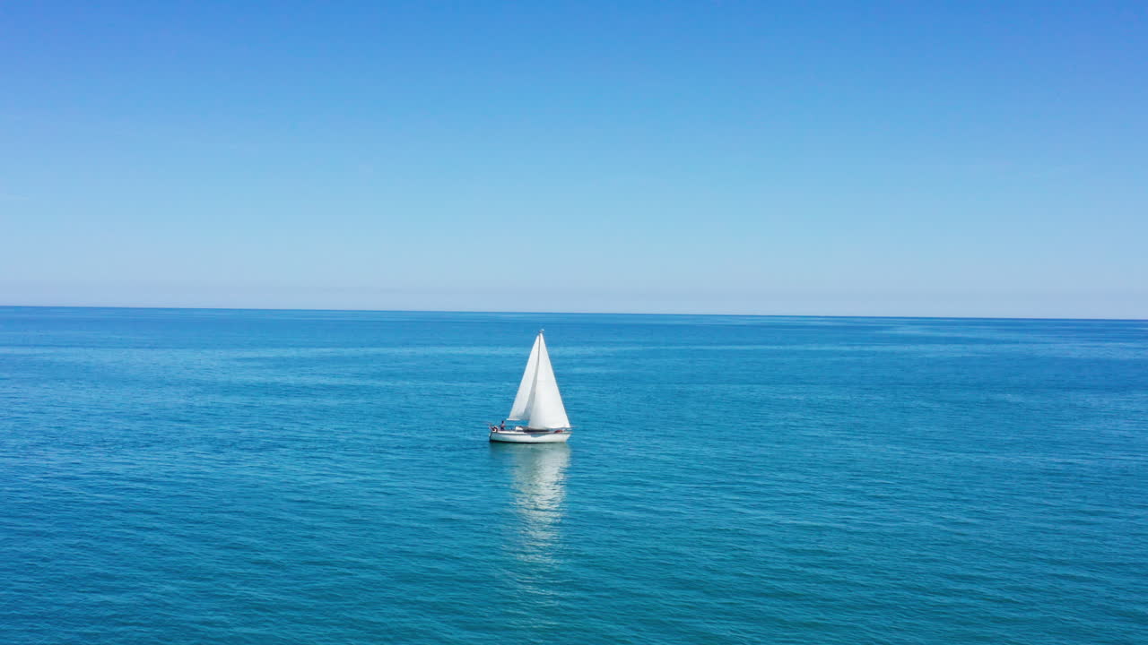 barco de vela en el mar mediterráneo con la plaga de valras en el fondo aéreo