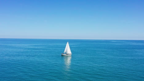 barco de vela en el mar mediterráneo con la plaga de valras en el fondo aéreo
