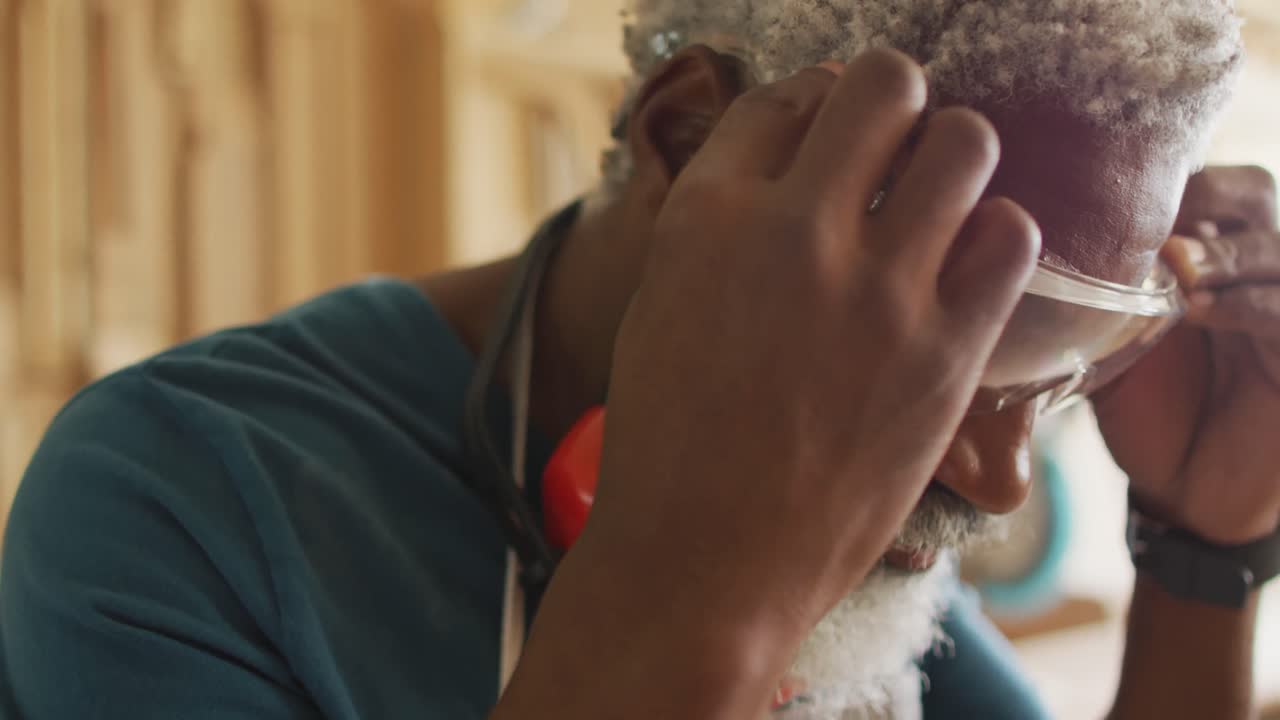 vista de cerca de un carpintero afroamericano que lleva gafas de seguridad en una carpintería