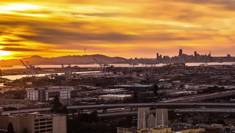 Golden-sunset-over-the-San-Francisco-Bay,-port,-highway-and-city-skyline---time-lapse