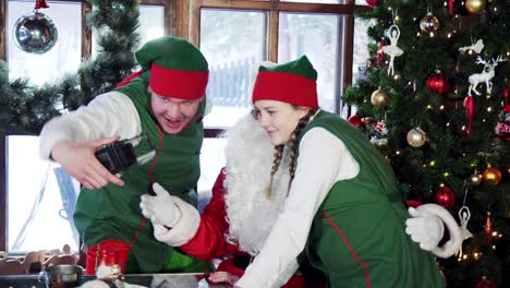 santa and elves doing selfie on christmas decoration background. fairy characters taking photos on retro camera