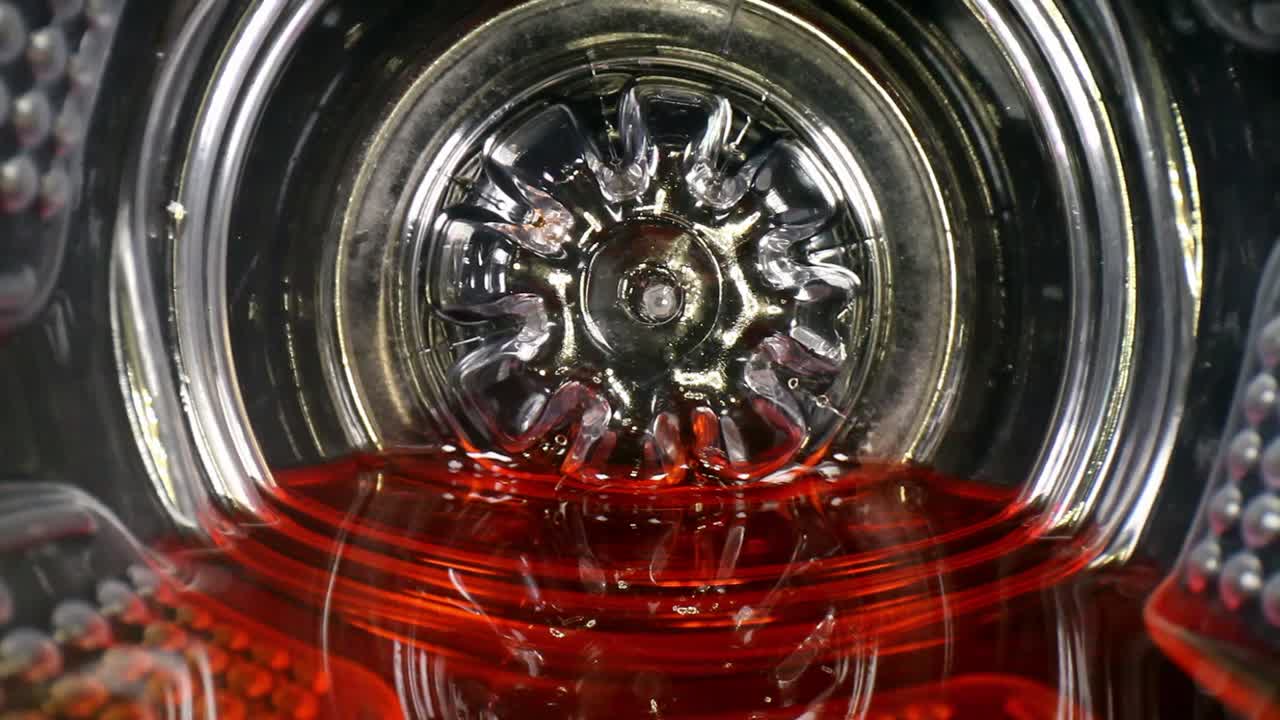 중앙에 흰색 빨대 - 빨간색 액체가 있는 스포츠 음료 또는 주스 병 바닥에서 천천히 빼냅니다.