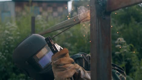 slow motion welder in mask and work wear fixes metal fence