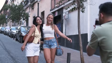 man photographing stylish female friends on city street