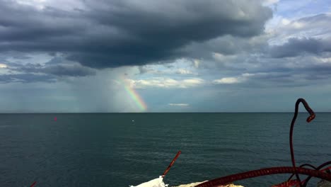 Kontrastierende-Gesperrte-Weitwinkelaufnahme-Mit-Blick-Auf-Den-Ontariosee-Mit-Einem-Regenbogen,-Der-Am-Horizont-Gegen-Den-Düsteren-Himmel-Erscheint