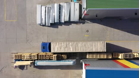 trucks with semi-trailers stand on the parking lot of the logistics park with loading hub and wait for load and unload goods at warehouse ramps at sunset