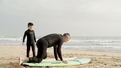 padre y hijo pequeño acostados en la tabla de surf