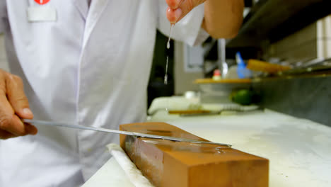 cocinero masculino afilando un cuchillo en una piedra de afilar en la cocina 4k